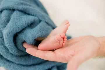 A close-up of a parent holding newborn baby feet showing the wrinkles on the bottom of the foot and...