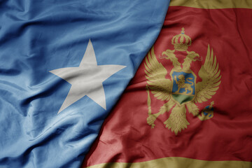big waving national colorful flag of montenegro and national flag of somalia .