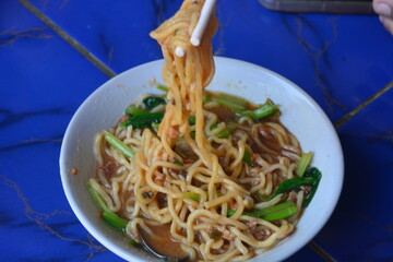 Photo of chicken noodles topped with dumplings, soy sauce chicken and mustard greens