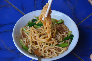 Photo of chicken noodles topped with dumplings, soy sauce chicken and mustard greens