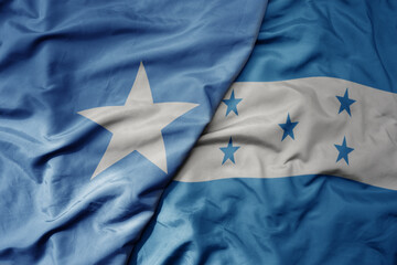 big waving national colorful flag of honduras and national flag of somalia .