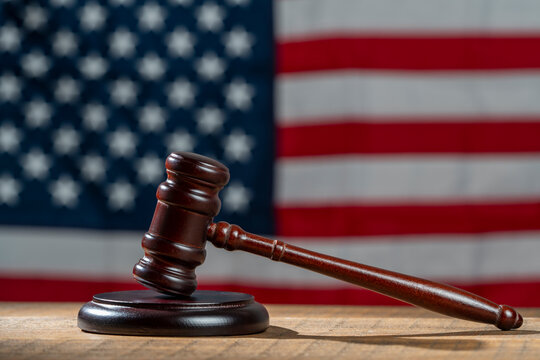 Wooden judge gavel and soundboard on the American flag background, closeup