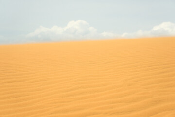 Sand dune in the desert with clouds in the background.