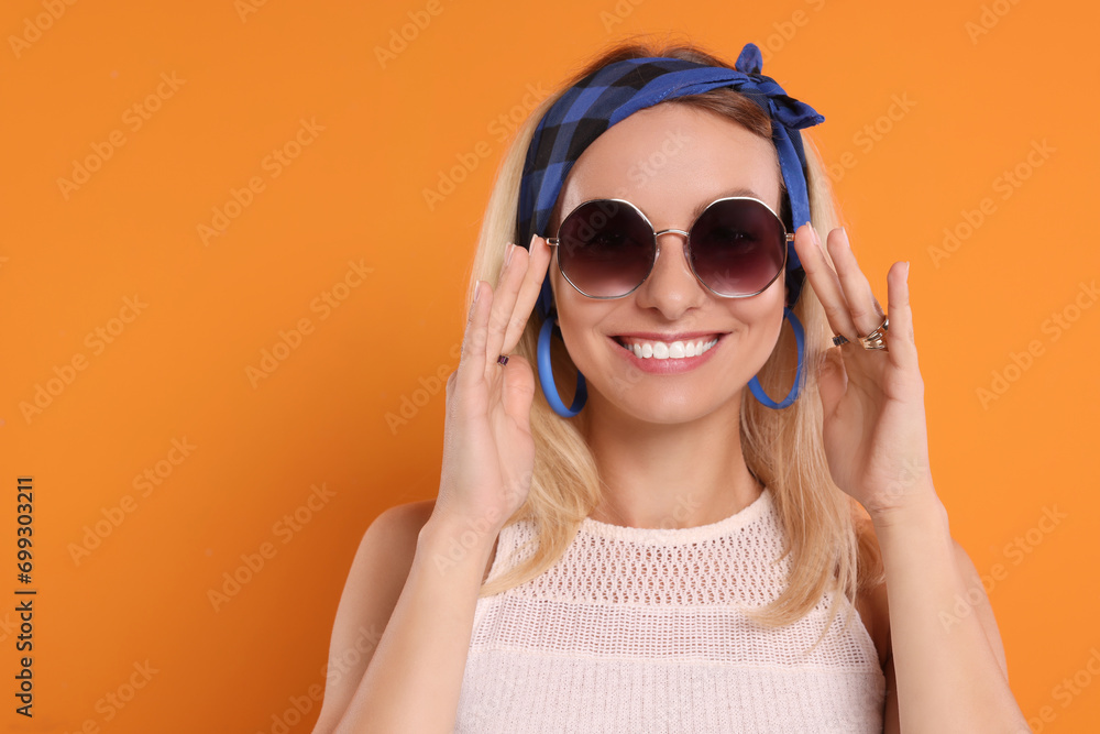 Sticker Portrait of smiling hippie woman in sunglasses on orange background. Space for text