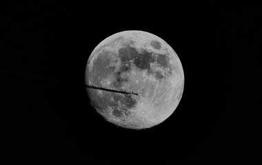 Airplane crossing in the direction of the moon.