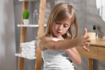 Suffering from allergy. Little girl scratching her arm in bathroom, space for text