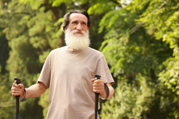 Senior man with Nordic walking poles outdoors, space for text. Low angle view