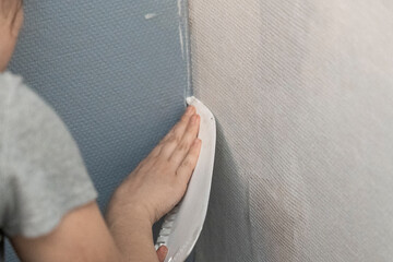 Careful Craftsmanship: Young Woman Applies Glassfiber Wallpaper, Elevating Walls with Meticulous...