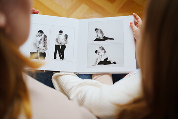 mother and daughter flips through a book with photos of dad and pregnant mom.