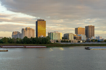 Obraz premium Sunset over the river barges and boats in Mississippi river to skyline of Baton Rouge, the state capital of Louisiana