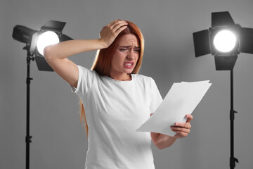 Casting call. Emotional woman with script performing on grey background