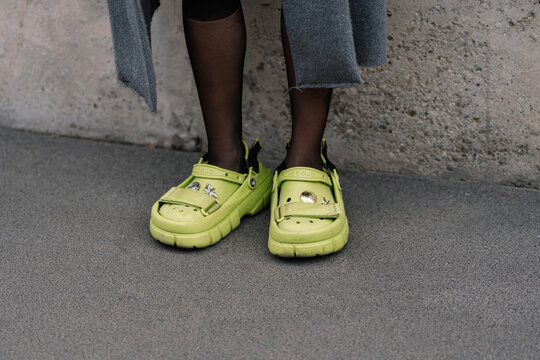Milan, Italy - February 23, 2023: woman wearing crocs classic clog Sankuanz lime punch. Fashion blogger outfit details, street style