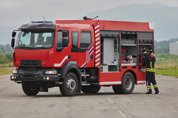 A firefighter meticulously prepares a modern firetruck for a mission to evacuate and respond to...