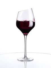 Red wine in a glass isolated on white background. Stylish wine glass with beveled edge