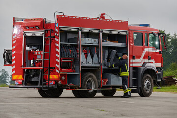 A firefighter meticulously prepares a modern firetruck for a mission to evacuate and respond to...