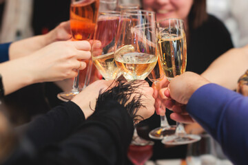 Group of guests celebrate and raise glasses, cheering with alcohol glasses with wine and champagne in the restaurant on corporate christmas birthday party event or wedding celebration - obrazy, fototapety, plakaty