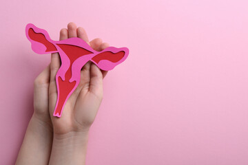 Reproductive medicine. Woman holding paper uterus on pink background, top view with space for text