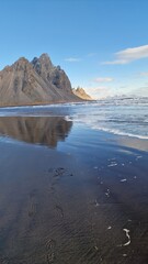 Stone mountain crests meeting the ocean in fantastic icelandic environment with natural black sand beach. Nordic stokksnes peninsula with vestrahorn mountain chain and beachfront, sightseeing.