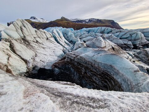 Frost covered Vatnajokull iceberg in Iceland with incredibly large glaciers painted white and blue. Arctic hills covered in snow and frozen icy cold water compose an icelandic picture.