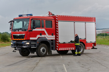 A firefighter meticulously prepares a modern firetruck for a mission to evacuate and respond to dangerous situations, showcasing the utmost dedication to safety and readiness in the face of a fire