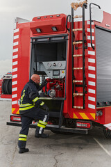 A firefighter meticulously prepares a modern firetruck for a mission to evacuate and respond to...
