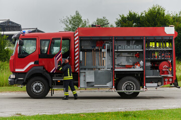 A firefighter meticulously prepares a modern firetruck for a mission to evacuate and respond to dangerous situations, showcasing the utmost dedication to safety and readiness in the face of a fire - obrazy, fototapety, plakaty