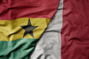 Fototapeta premium big waving national colorful flag of malta and national flag of ghana .