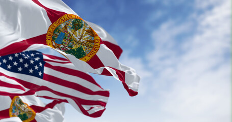 Flags of Florida and United States waving in the wind on a clear day