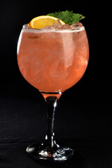 refreshing alcoholic drink with berries, ice vodka and gin, lemon peel served in glass cup on the counter on blurred background