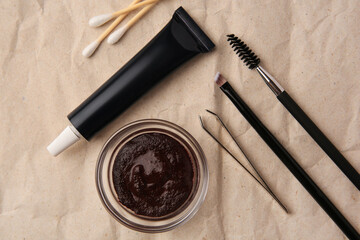 Flat lay composition with eyebrow henna and tools on crumpled paper