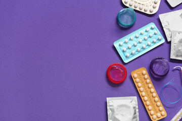 Contraceptive pills and condoms on violet background, flat lay with space for text. Different birth...