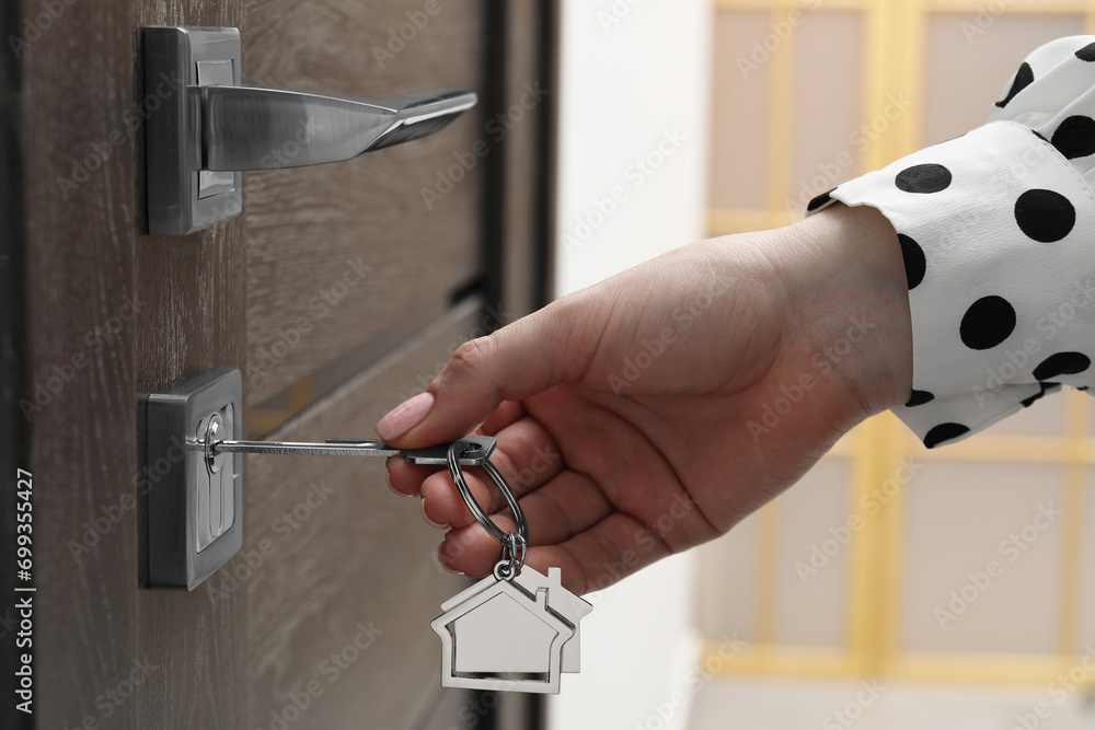 Wall mural Woman unlocking door with key, closeup view