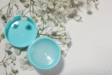 Lip balm and gypsophila on white textured background, flat lay. Space for text
