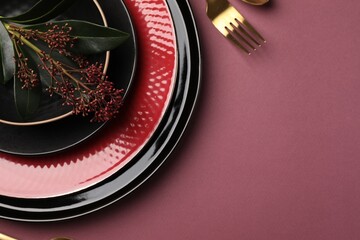 Stylish table setting with cutlery and floral decor on pink background, top view. Space for text