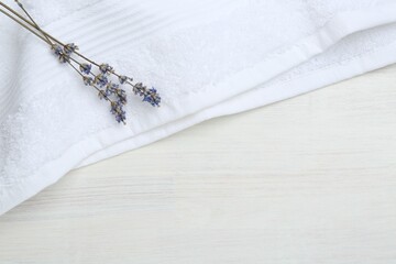 White terry towel and lavender flowers on light wooden table, top view. Space for text