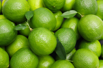 Many fresh limes with green leaves as background, top view © New Africa