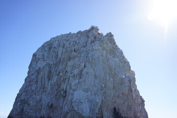 Large rock near Arch of Cabo San Lucas, bright blue sky and sun in corner