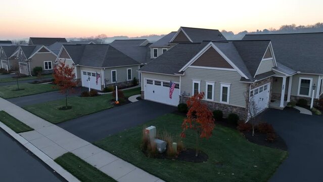 American flag on 55+ houses in retirement community in USA. Aerial establishing shot during foggy autumn morning.