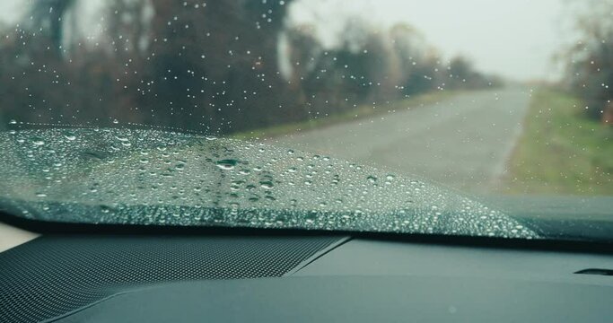 Focus on rain on windshield of car in light rain 