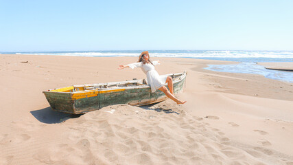 mujer sentada en un bote abandonado en la playa