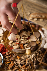 Ancient Chinese medicine and different herbal ingredients on table.