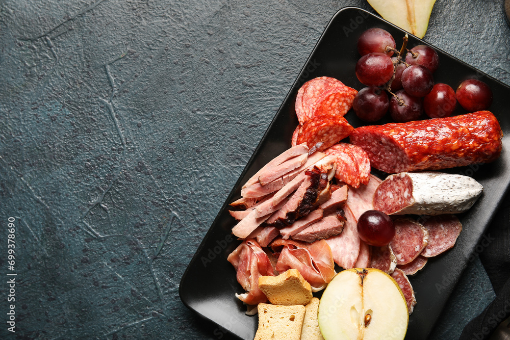 Wall mural Plate with assortment of tasty deli meats on black background