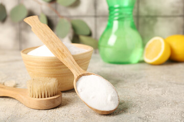Spoon of baking soda and cleaning brush on grunge table