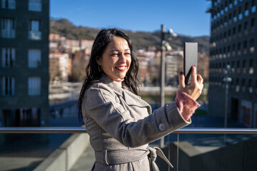 Fototapeta premium Close-up of elegant woman taking a selfie with her smartphone smiling.