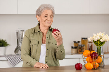 Fototapeta na wymiar Senior woman with apple in kitchen