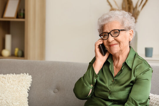 Senior woman talking by mobile phone at home