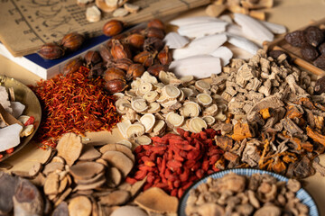 Ancient Chinese medicine and different herbal ingredients on table.