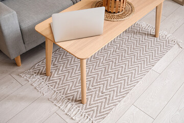 Interior of living room with stylish rug and laptop on coffee table