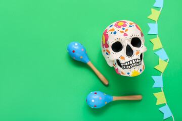 Painted human skull for Mexico's Day of the Dead (El Dia de Muertos) with maracas and garland on...