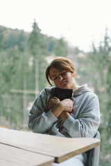 Fototapeta premium A girl reads the Bible against the background of a beautiful forest panorama. Christian woman holds holy bible in hands. Concept for faith, spirituality and religion.